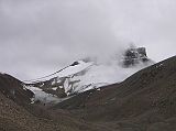 Tibet Kailash 09 Kora 04 Last Cloudy View of Kailash Across the valley, a trail branches off to the southeast over the snow-covered Khandro Sanglam La, the Secret Path of the Dakini Khandroma). This alterative route around Kailash bypasses the D�lma La, which tradition says can only be crossed if you have completed 12 previous koras.